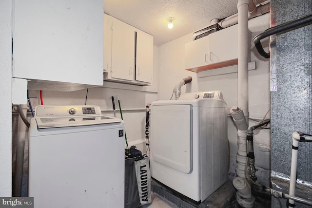 washroom featuring cabinet space, washer and clothes dryer, and a textured ceiling