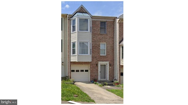 multi unit property with brick siding, an attached garage, and concrete driveway