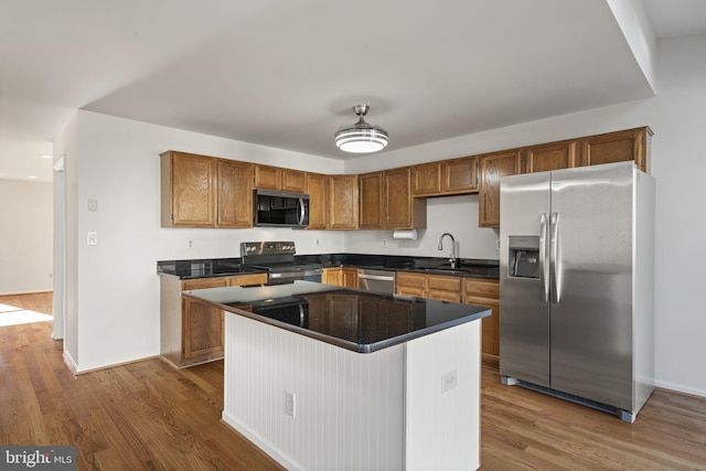 kitchen with dark wood-type flooring, dark countertops, appliances with stainless steel finishes, and a sink