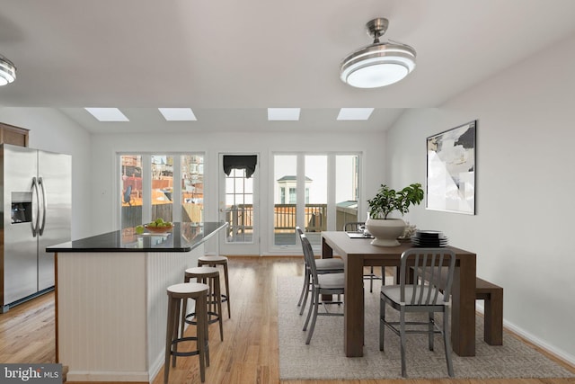 dining room with light wood-style floors and vaulted ceiling