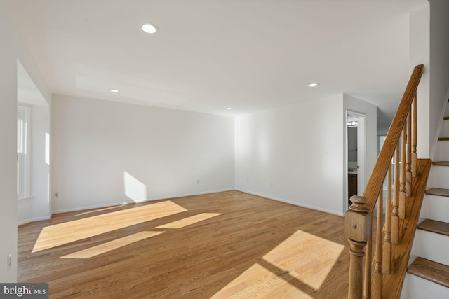 spare room featuring stairway, recessed lighting, light wood-style floors, and baseboards