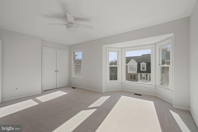 interior space featuring visible vents, a closet, carpet, baseboards, and ceiling fan