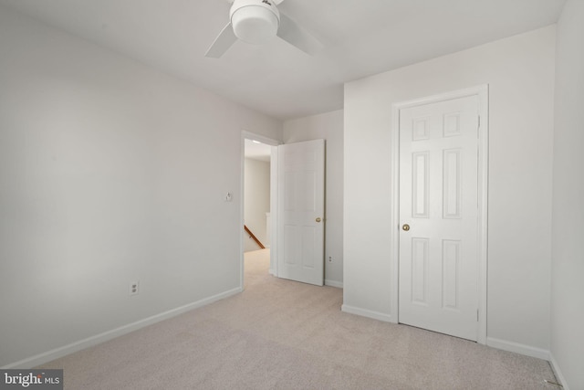 unfurnished bedroom featuring a ceiling fan, light colored carpet, and baseboards