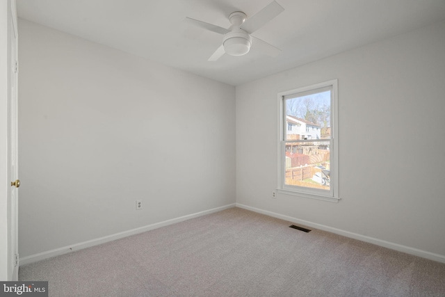 carpeted spare room featuring visible vents, baseboards, and a ceiling fan