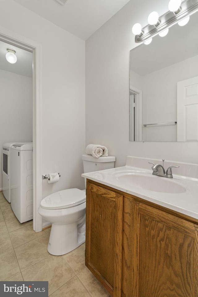 half bath with vanity, tile patterned floors, toilet, and washing machine and dryer