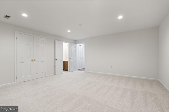 unfurnished bedroom with visible vents, connected bathroom, baseboards, light colored carpet, and recessed lighting