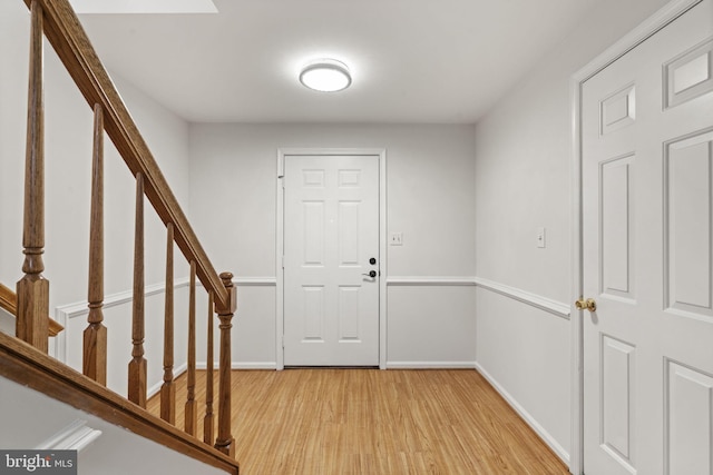 foyer with baseboards, light wood-style flooring, and stairs