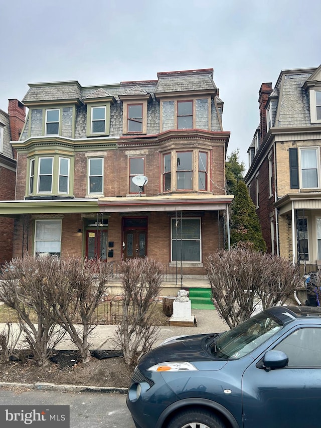 victorian home featuring a high end roof, brick siding, and mansard roof