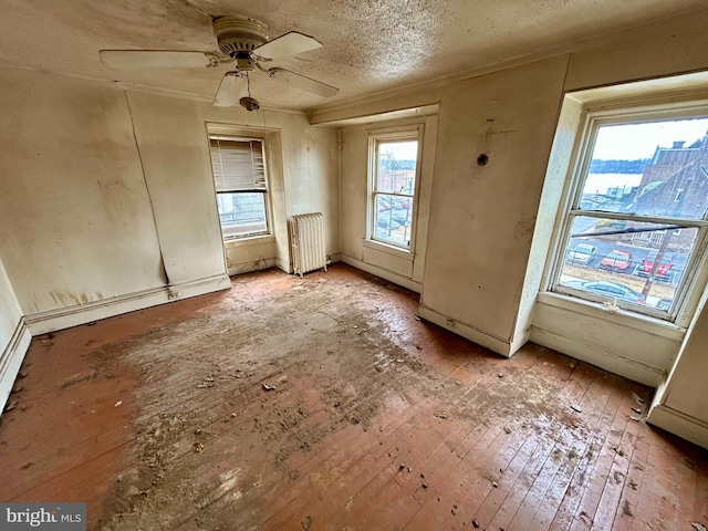 spare room with radiator, light wood-style floors, a textured ceiling, and a ceiling fan