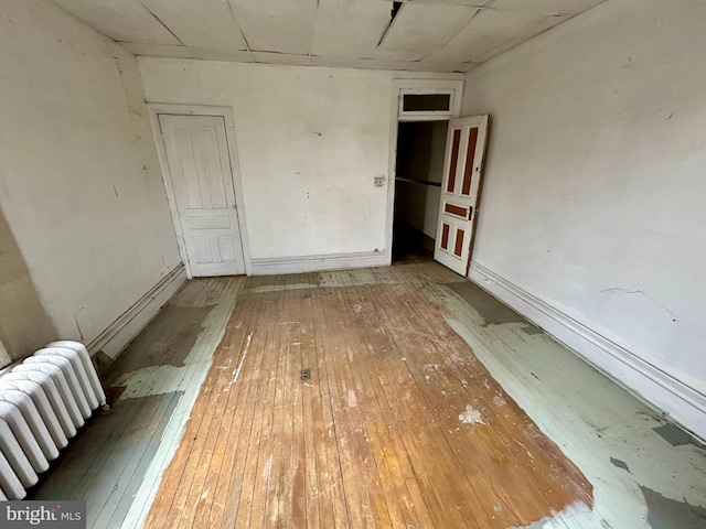 unfurnished room with radiator heating unit, baseboards, and wood finished floors