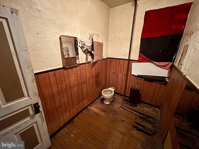 interior space with a wainscoted wall, wooden walls, and wood finished floors