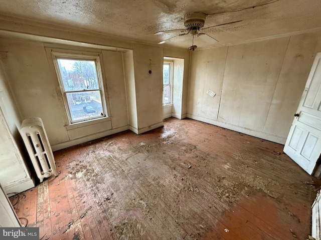 spare room featuring ceiling fan, radiator heating unit, and wood finished floors