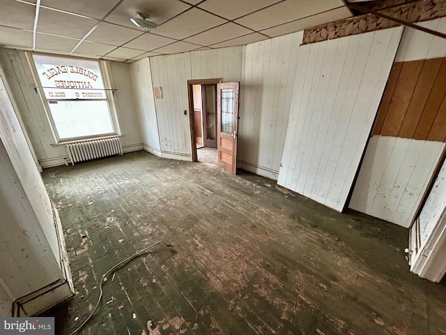 spare room featuring radiator heating unit, dark wood finished floors, and a drop ceiling