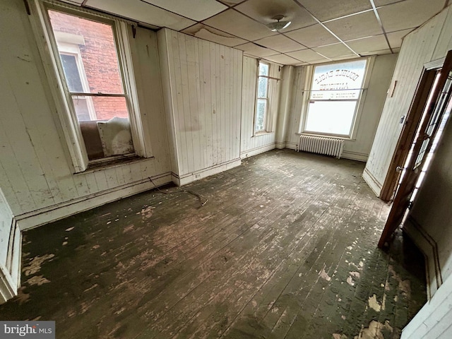 misc room with a paneled ceiling, radiator heating unit, and wood finished floors