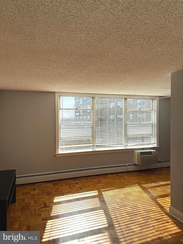 unfurnished room featuring a healthy amount of sunlight, a textured ceiling, baseboards, and a baseboard radiator