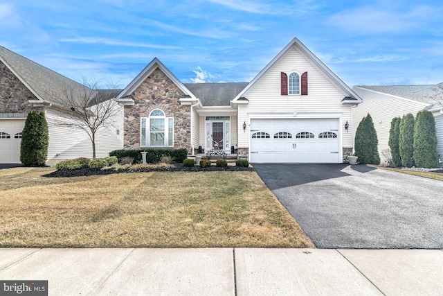 view of front of home featuring a garage, stone siding, a front yard, and driveway