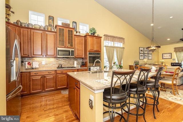 kitchen featuring appliances with stainless steel finishes, a sink, light wood-style flooring, and a kitchen bar