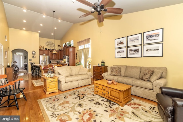 living room featuring arched walkways, high vaulted ceiling, light wood-style flooring, recessed lighting, and a ceiling fan