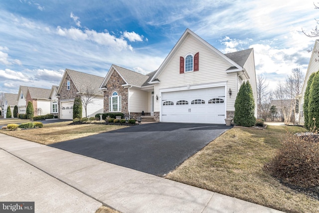 traditional-style home with aphalt driveway, stone siding, and a garage