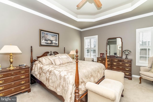 bedroom featuring a tray ceiling, light colored carpet, crown molding, and ceiling fan