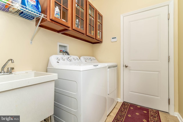 laundry room featuring light tile patterned floors, a sink, baseboards, washer and dryer, and cabinet space