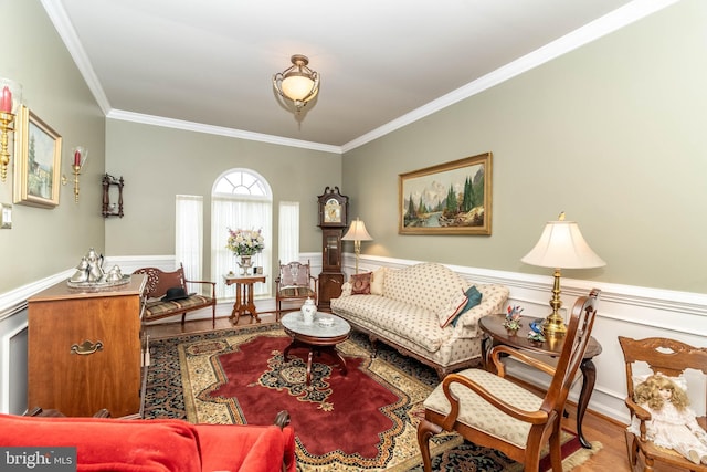 living area featuring ornamental molding, wainscoting, and wood finished floors