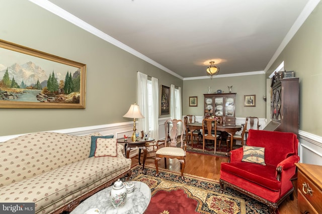 living room with a wainscoted wall, ornamental molding, and wood finished floors