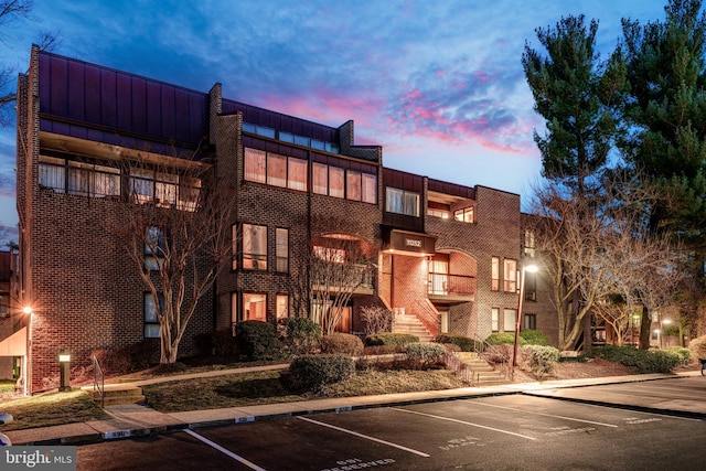 view of property with stairs and uncovered parking