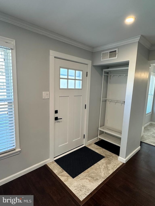 entrance foyer with hardwood / wood-style flooring, visible vents, and crown molding