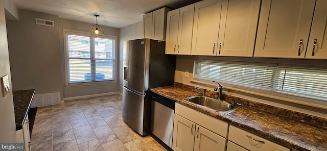 kitchen featuring visible vents, hanging light fixtures, appliances with stainless steel finishes, a sink, and dark stone countertops