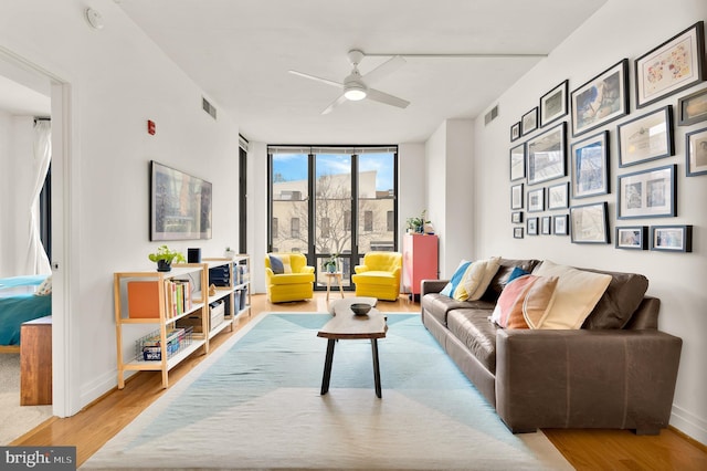 living room featuring visible vents, expansive windows, baseboards, and wood finished floors