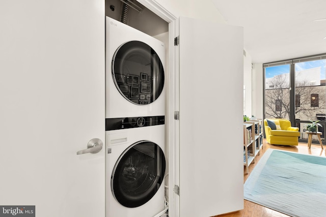 laundry area with stacked washer / dryer, laundry area, and wood finished floors