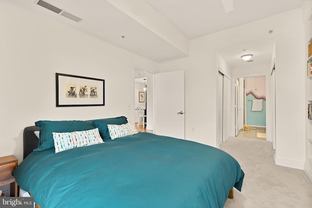 bedroom with light carpet, visible vents, baseboards, and a closet