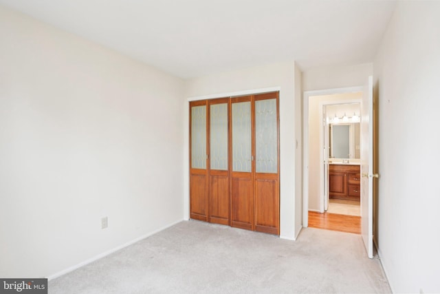 unfurnished bedroom with a closet, light colored carpet, and baseboards