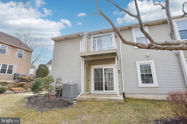 rear view of house featuring a balcony, cooling unit, and a yard