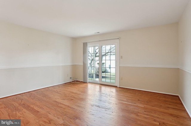 spare room with baseboards and wood finished floors