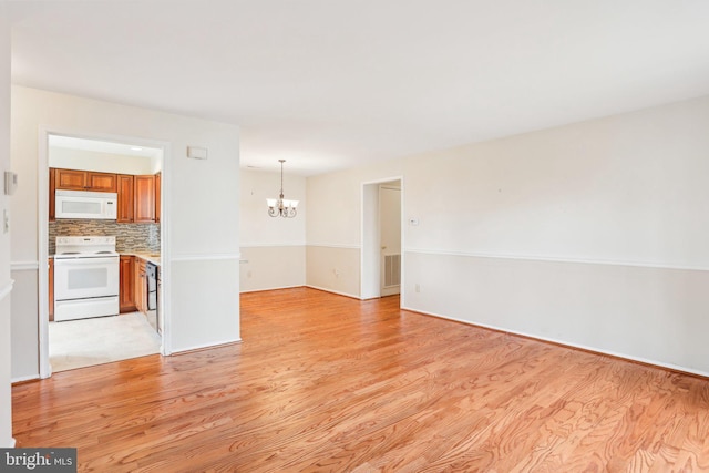 unfurnished living room featuring visible vents, light wood-type flooring, and an inviting chandelier