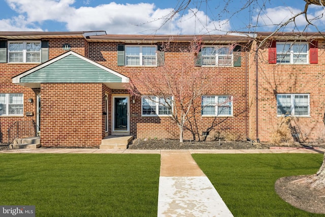 townhome / multi-family property with a front lawn and brick siding