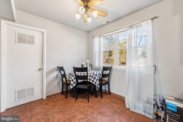 tiled dining room with visible vents, ceiling fan, and baseboards