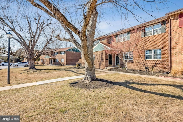 view of front facade with brick siding and a front yard