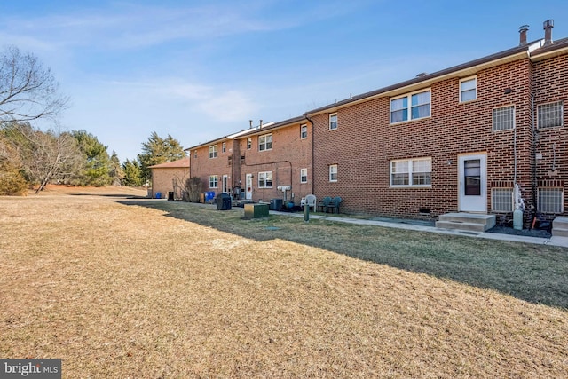 rear view of property with a lawn and brick siding