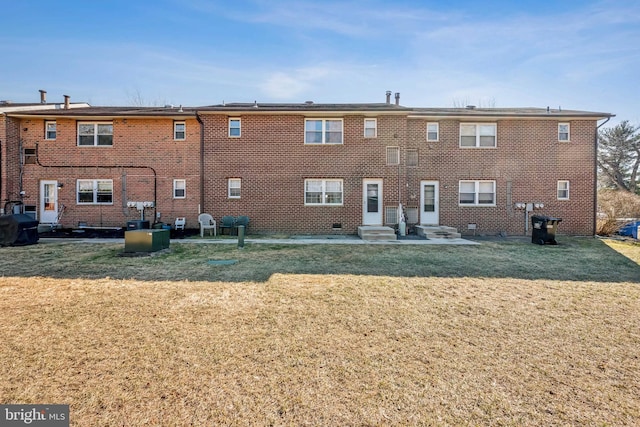 back of house with entry steps, brick siding, and a yard