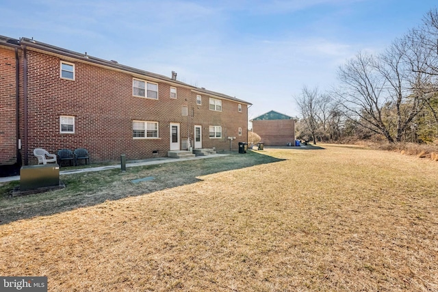 rear view of property with a yard and brick siding