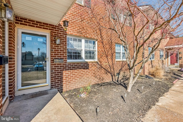 property entrance with a patio and brick siding