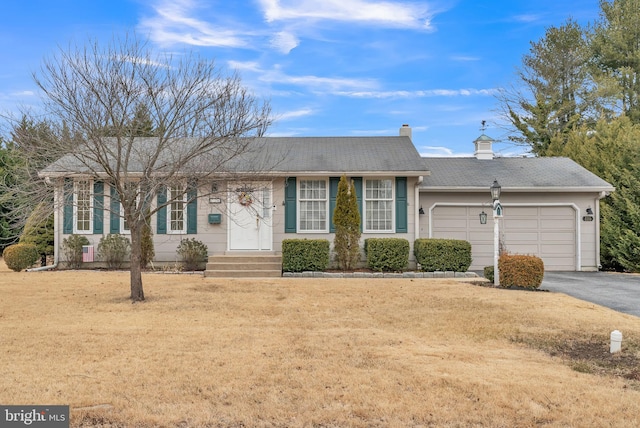 ranch-style house with a garage, a chimney, aphalt driveway, and a front yard