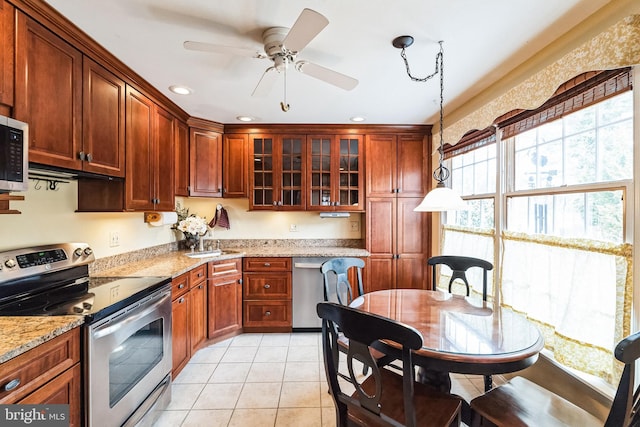 kitchen with light tile patterned floors, stainless steel appliances, hanging light fixtures, glass insert cabinets, and light stone countertops