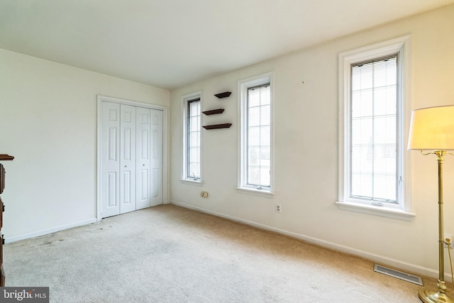 unfurnished bedroom with baseboards, a closet, visible vents, and light colored carpet