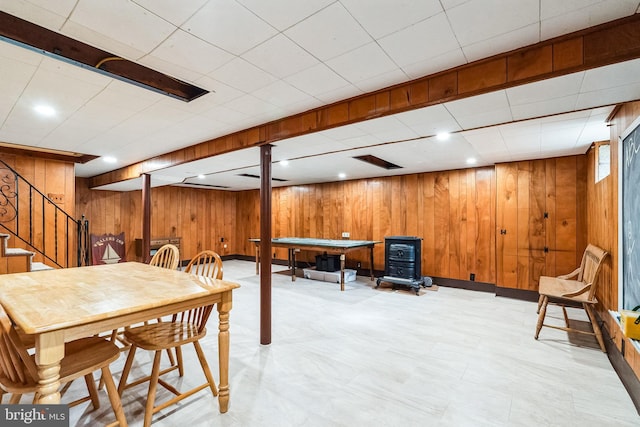 dining room featuring light floors, recessed lighting, stairway, a wood stove, and wooden walls