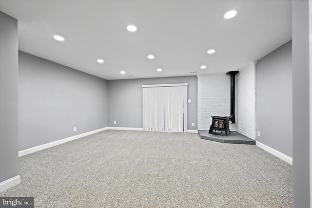 basement featuring baseboards, carpet, a wood stove, and recessed lighting