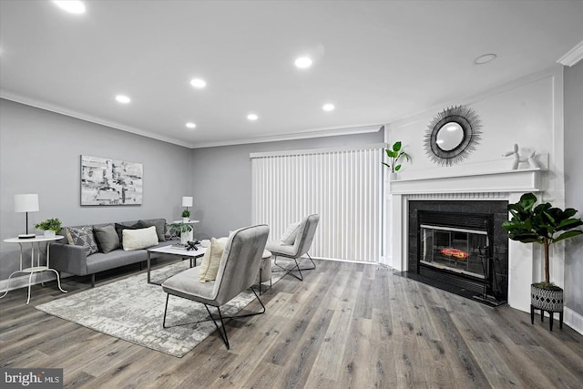 living area featuring baseboards, a fireplace with flush hearth, ornamental molding, wood finished floors, and recessed lighting